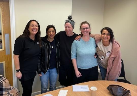 Francesca stands with four women who helped make the audio story. They have their arms around each other's shoulders and they're smiling at the camera.